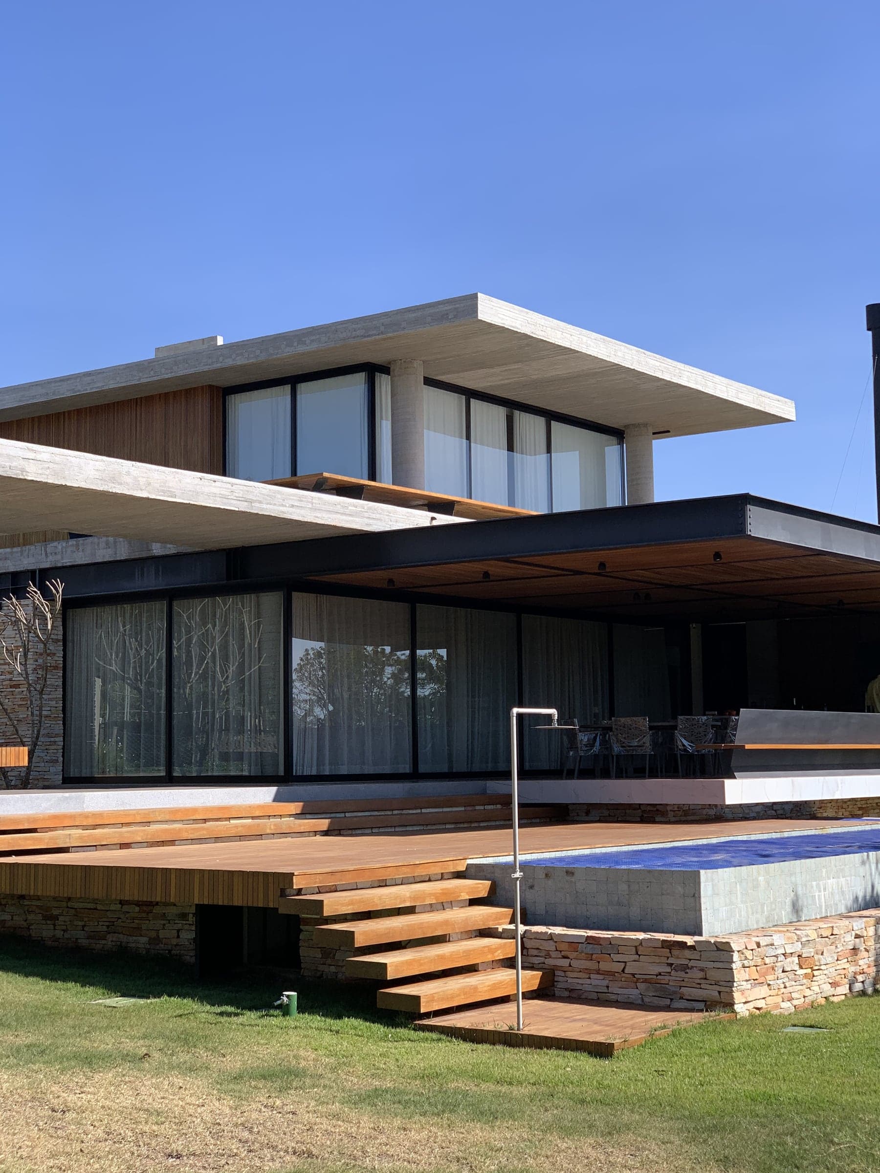 Residência com planos de concreto, panos de vidro no térreo e deck com piscina