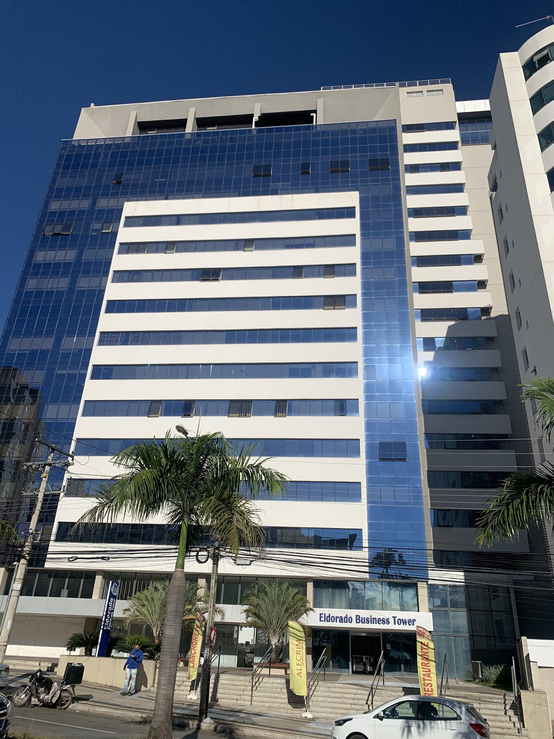 Torre comercial com pele de vidro azul e faixas horizontais de janelas